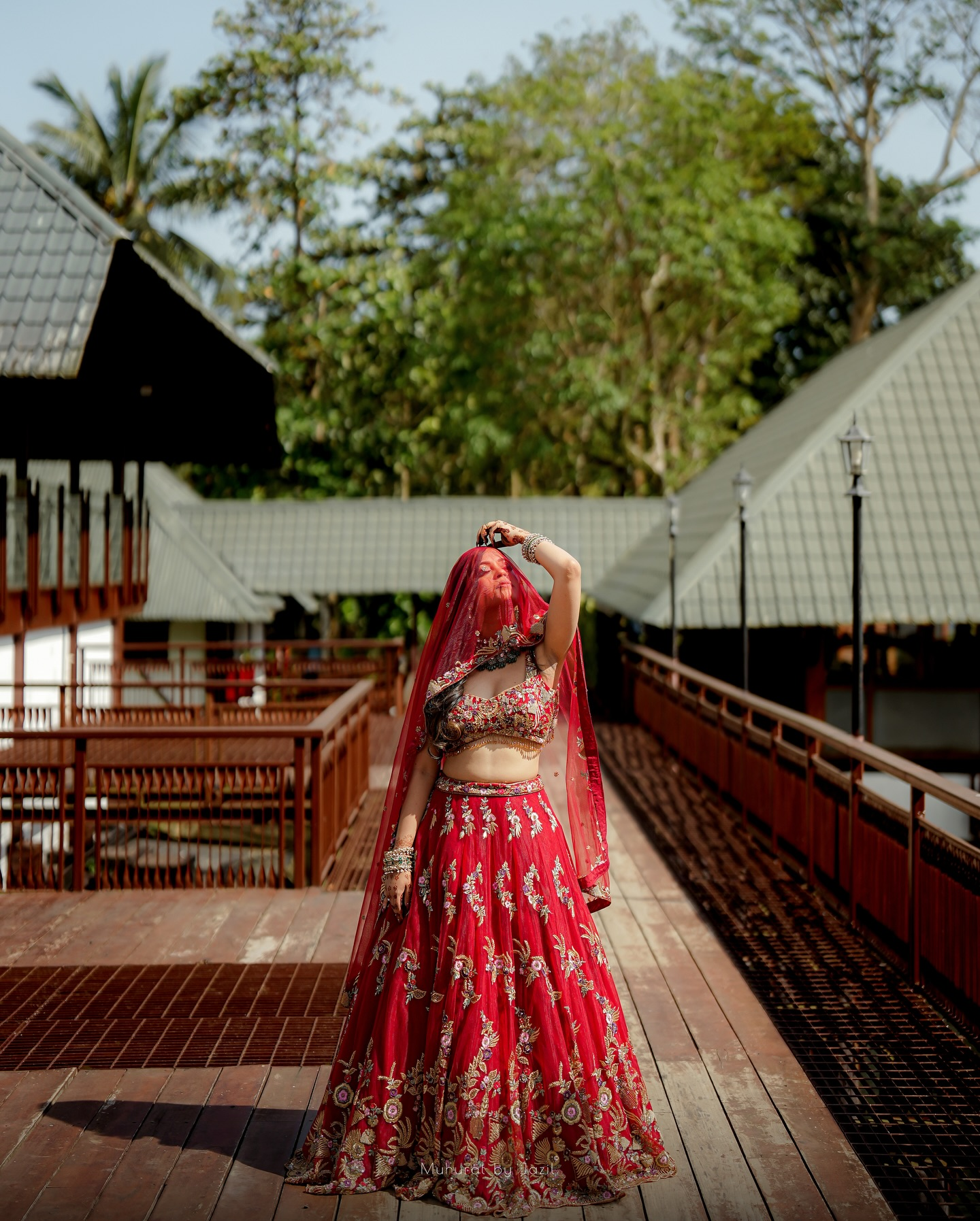 A bride in a red lehenga standing in warm afternoon light